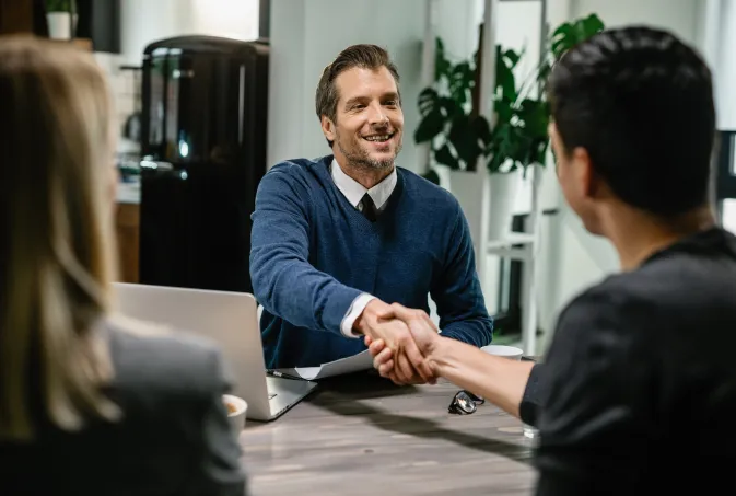 happy financial consultant greeting his clients while meeting them their home me are shaking hands